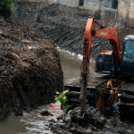 Plang imbauan larangan membuang sampah sembarangan yang terpasang di dekat area aliran sungai.
