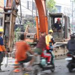 Potret warga lokal dan pengendara motor melintasi pembatas proyek perbaikan di Jalan Raya M. Toha Karawaci yang sedang diekskavasi untuk penguatan struktur beton.