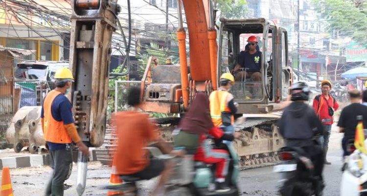 Potret warga lokal dan pengendara motor melintasi pembatas proyek perbaikan di Jalan Raya M. Toha Karawaci yang sedang diekskavasi untuk penguatan struktur beton.
