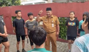 Foto Kadispora Kota Tangerang Kaonang saat meninjau langsung tes fisik atlet PPLPD di GOR Nambo Jaya dengan latar belakang atlet yang sedang berlari.